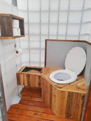 The interior of a Portable composting toilet unit including recycled wood floors and stainless steel details. Waterless, dry set up using sawdust.